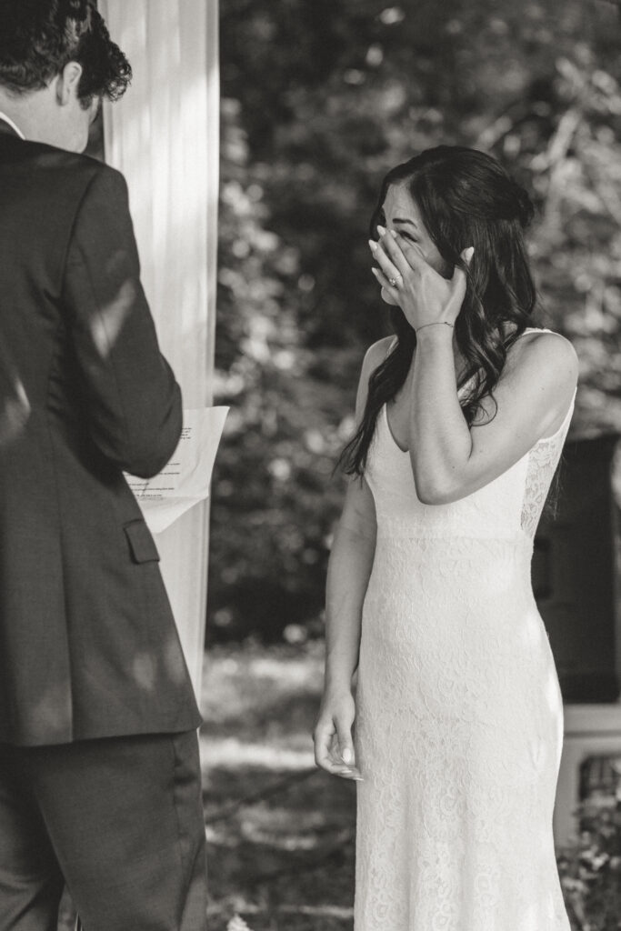 The bride wiping away a tear as the groom reads his vows