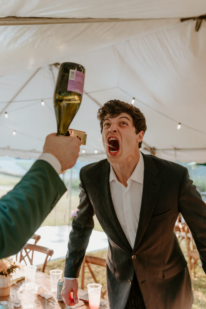 The groom's best friend shooting champagne into the groom's mouth