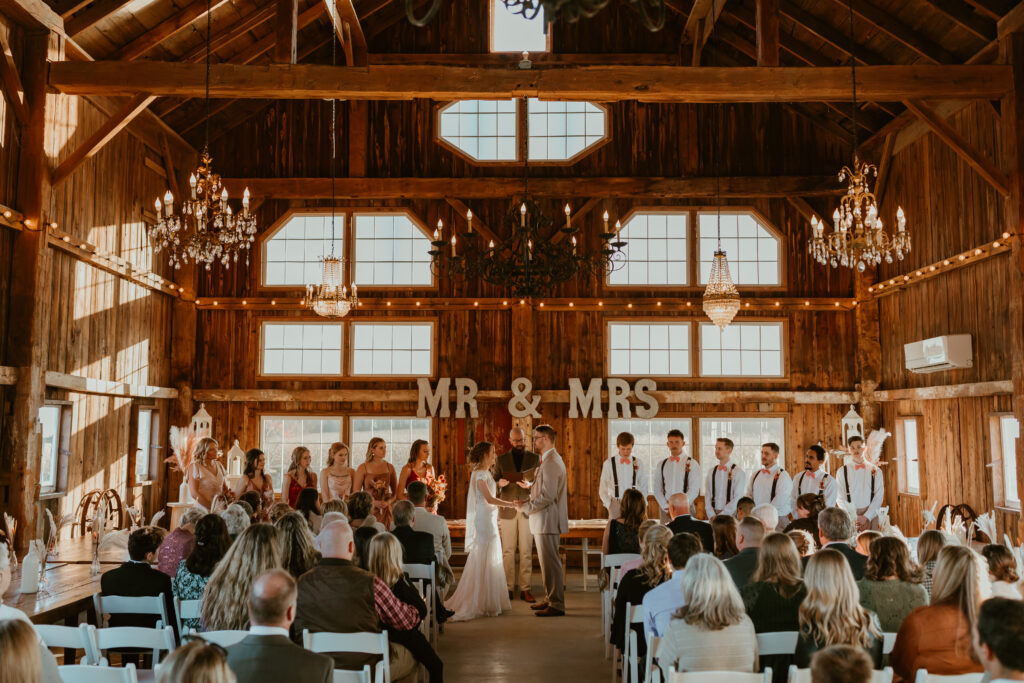 A wedding ceremony takes place inside of a barn.