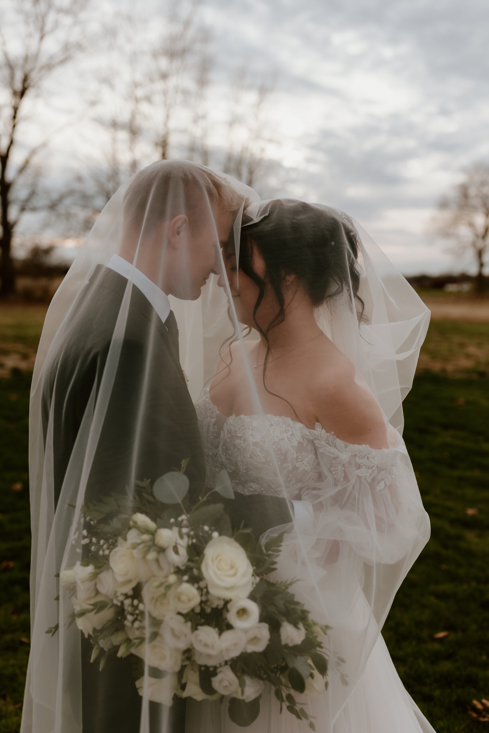 A bride and groom sharing an intimate moment underneath the bride's veil